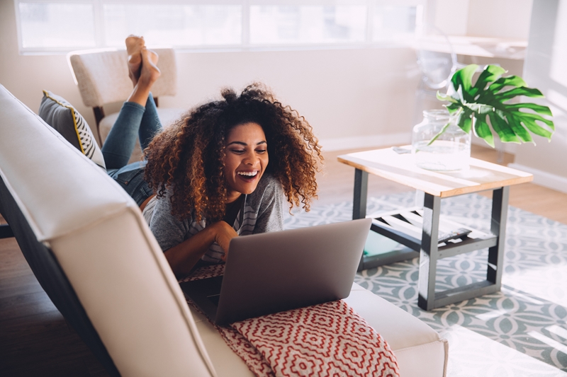 Woman laughing at laptop.